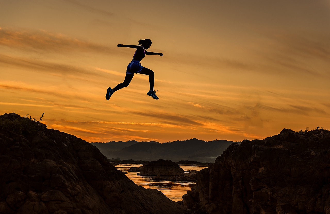 Image of woman jumping between mountaintops