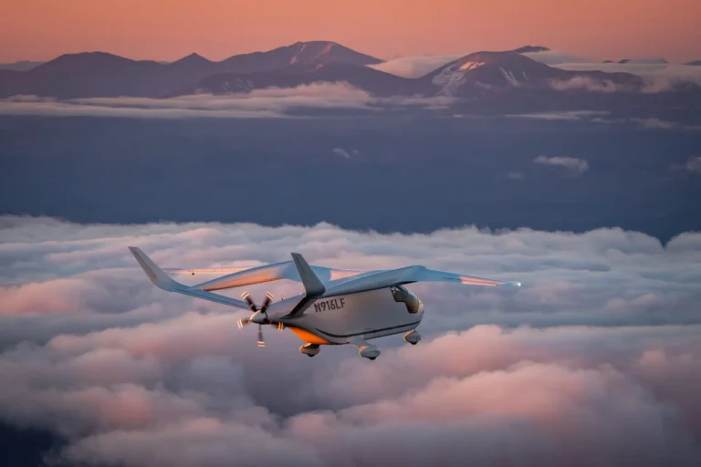 BETA CX300 flying above the clouds with mountains in the background